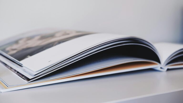 Close-up of an open magazine lying on a white surface, showcasing glossy pages.